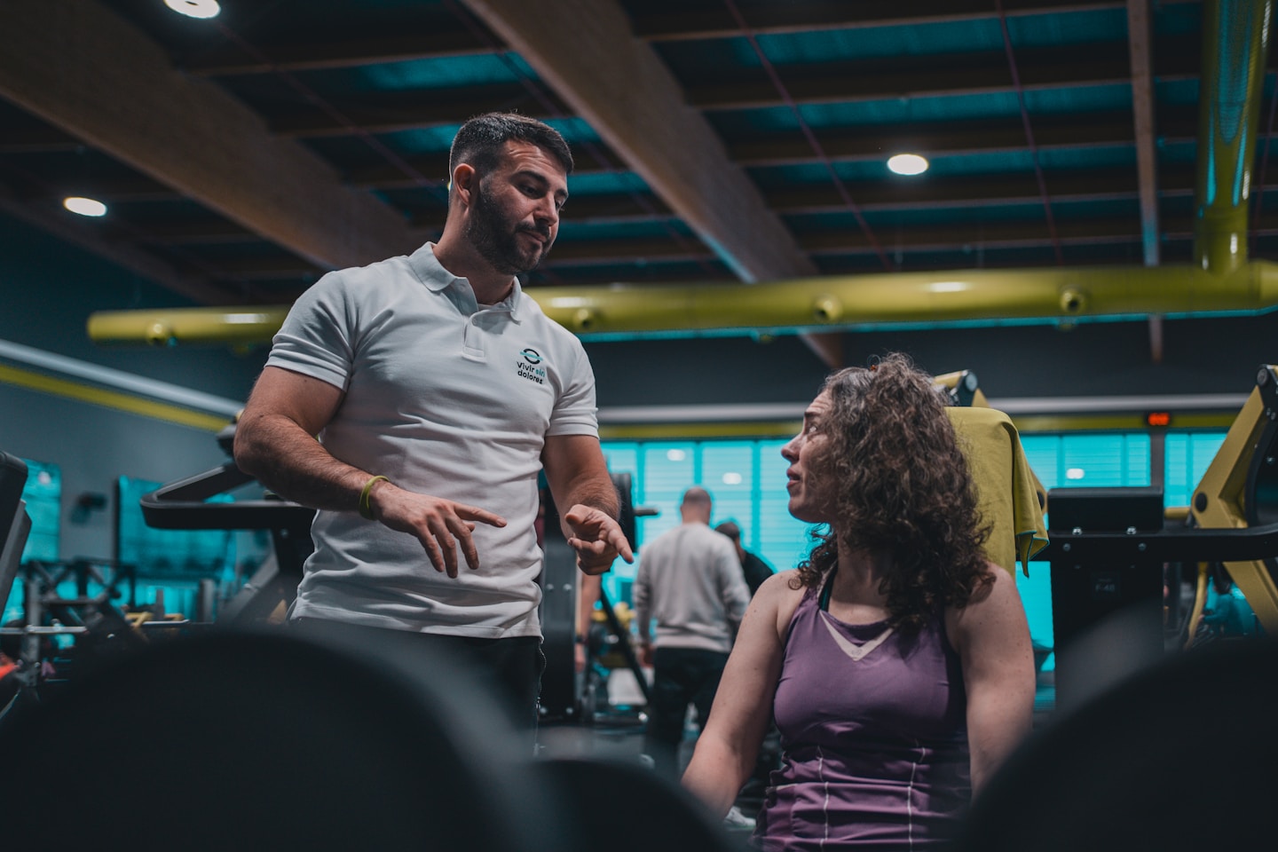 Sesión de entrenamiento en el gimnasio con un entrenador personal, enfocada en el rendimiento y el bienestar físico.