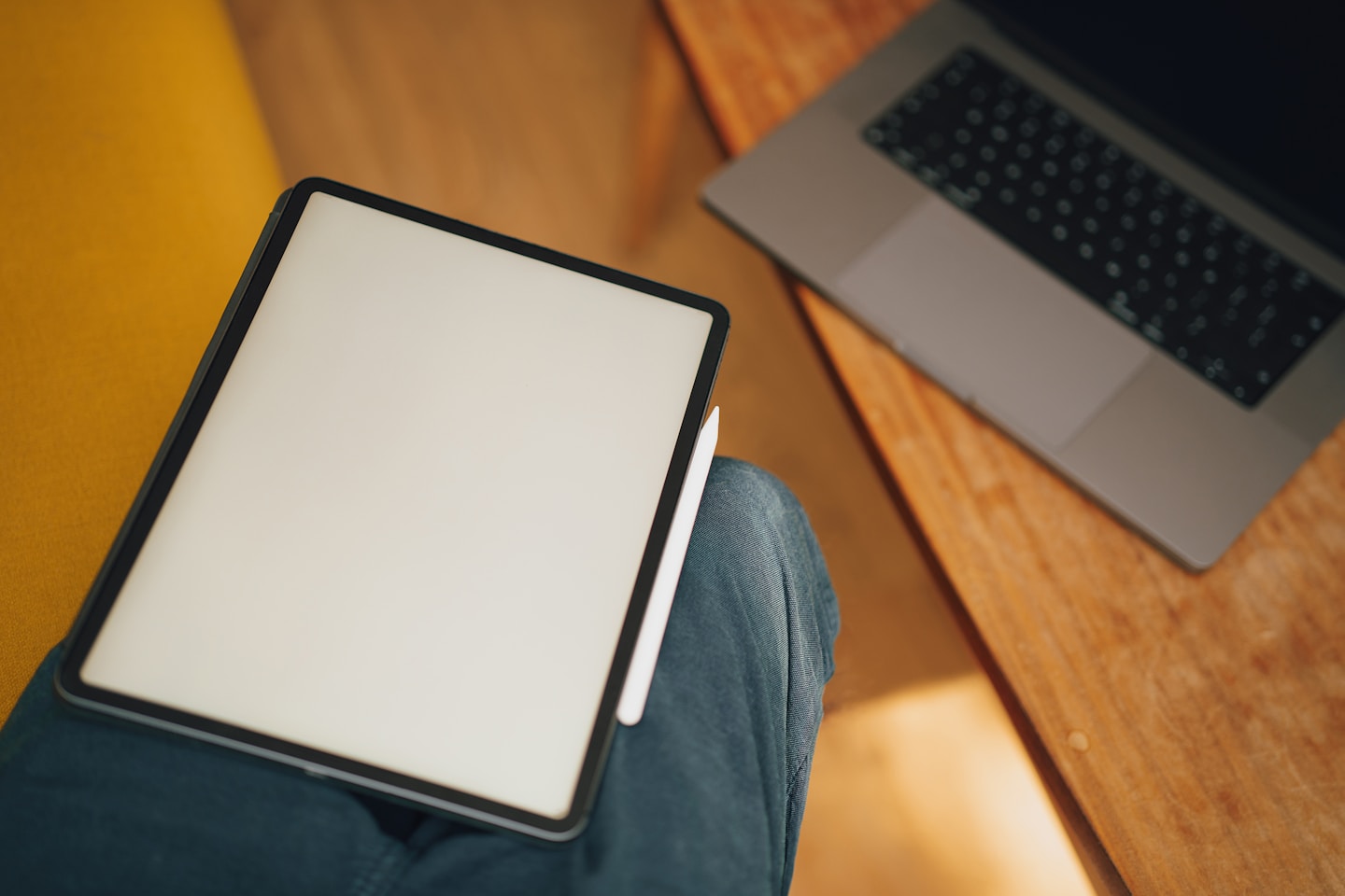 Graphic tablet on lap. Home living room interior. Empty screen mockup. Laptop wooden table.